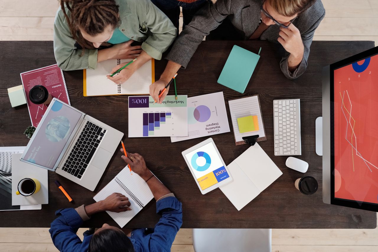 Vue plongeante d'une équipe diversifiée travaillant ensemble sur un projet dans un bureau moderne.
